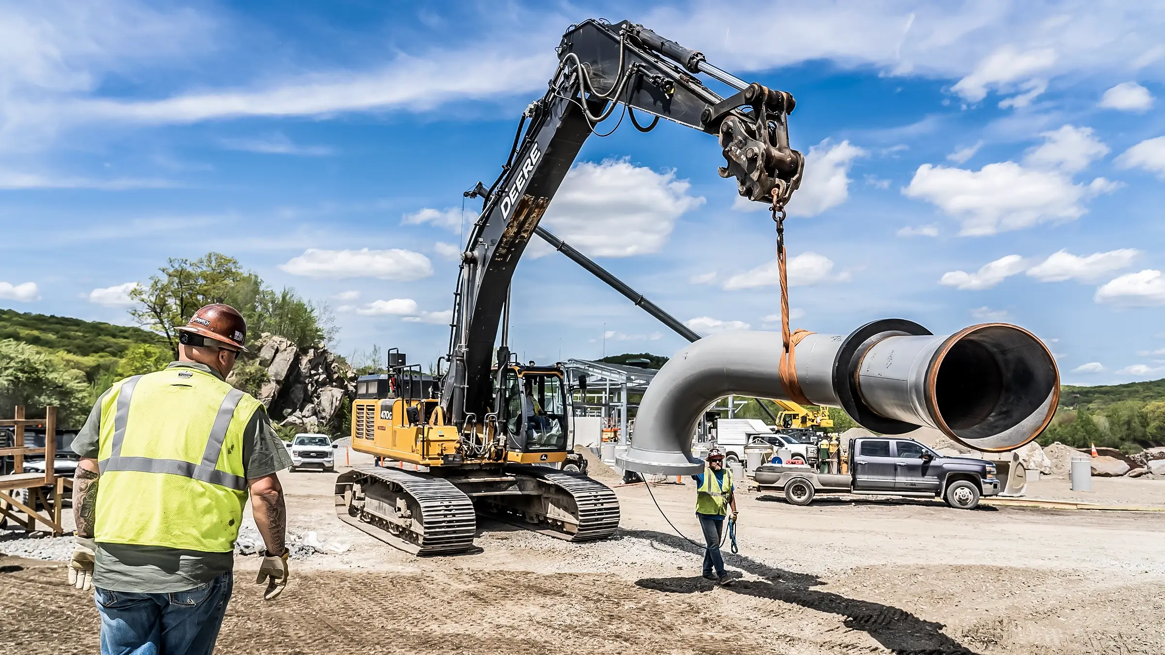 An excavator lifts a portion of pipe into place on a facilties jobsite.