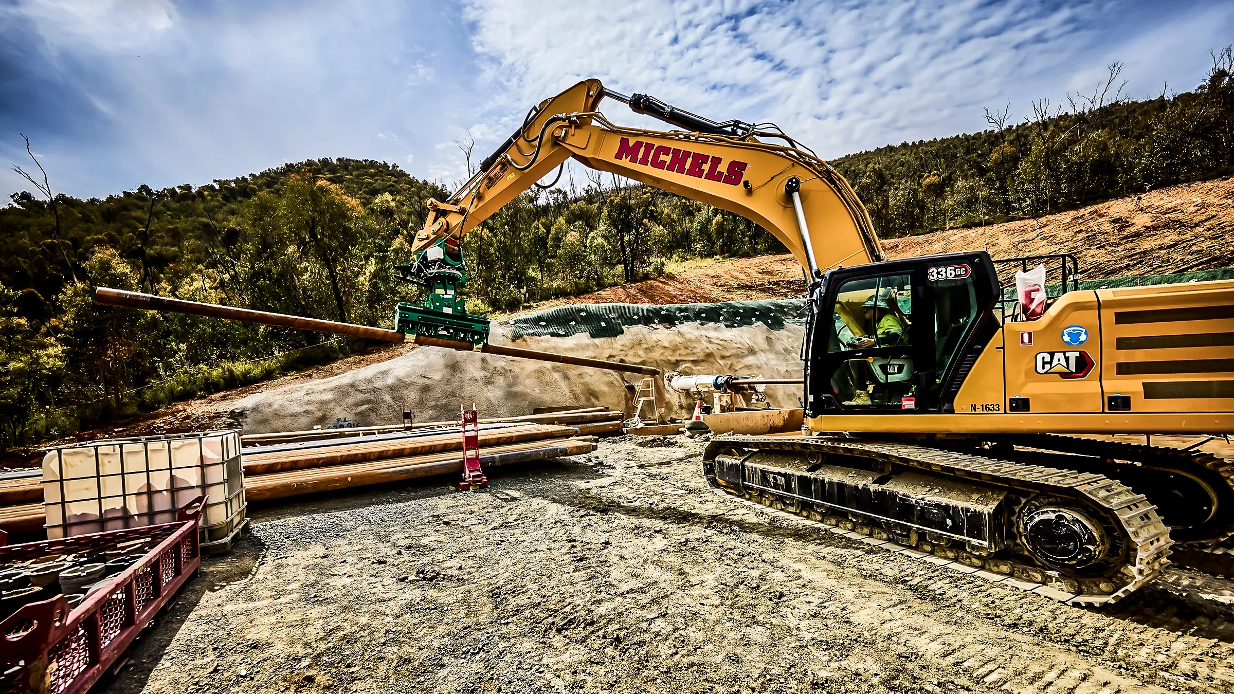 An excavator lifts a pipe into place.