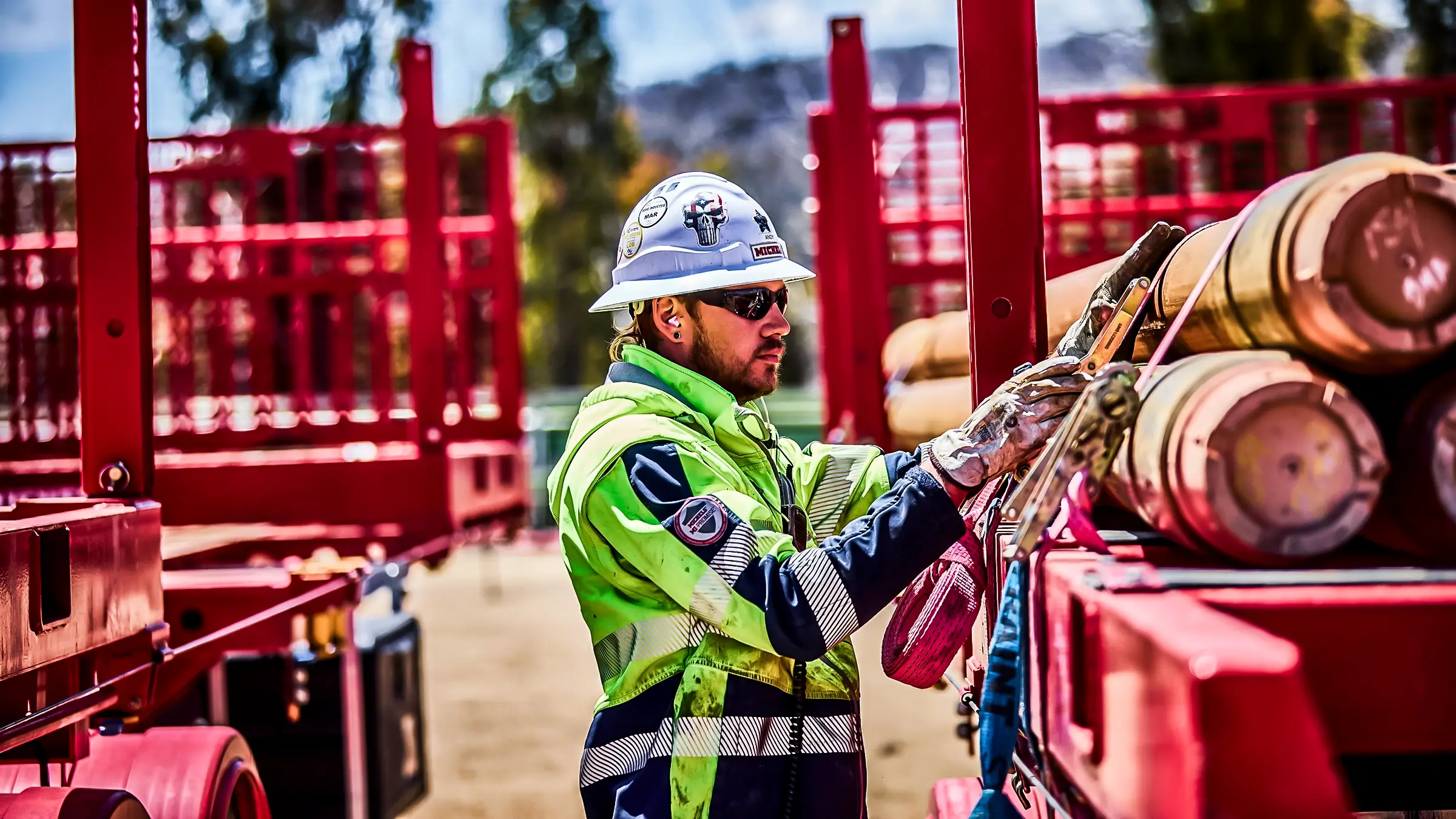 A man straps down a pile of pipes.