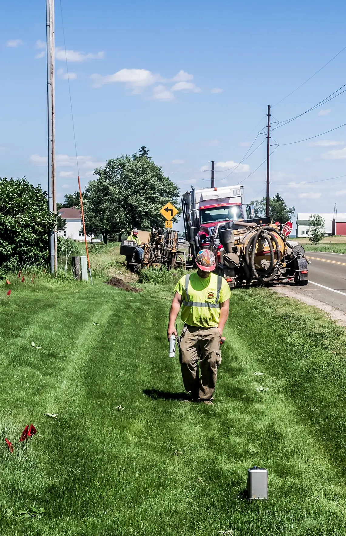 A crew member walks near a grassy roadside project.