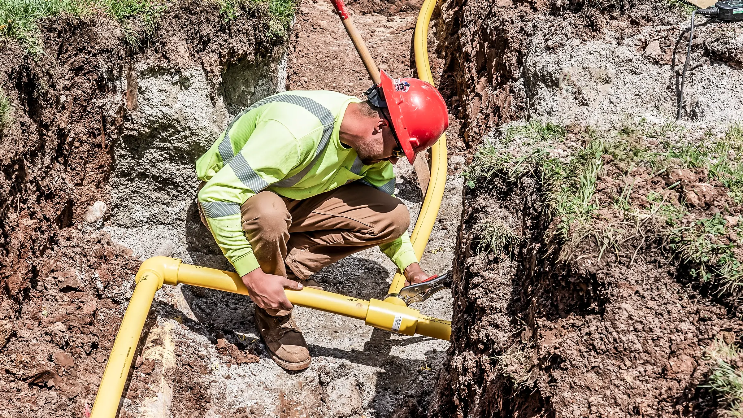 Crew member in small ditch adjusts small diameter pipeline.