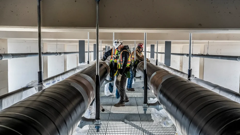 Several workers operate on two pipelines under the 10th Ave bridge in Minnesota.