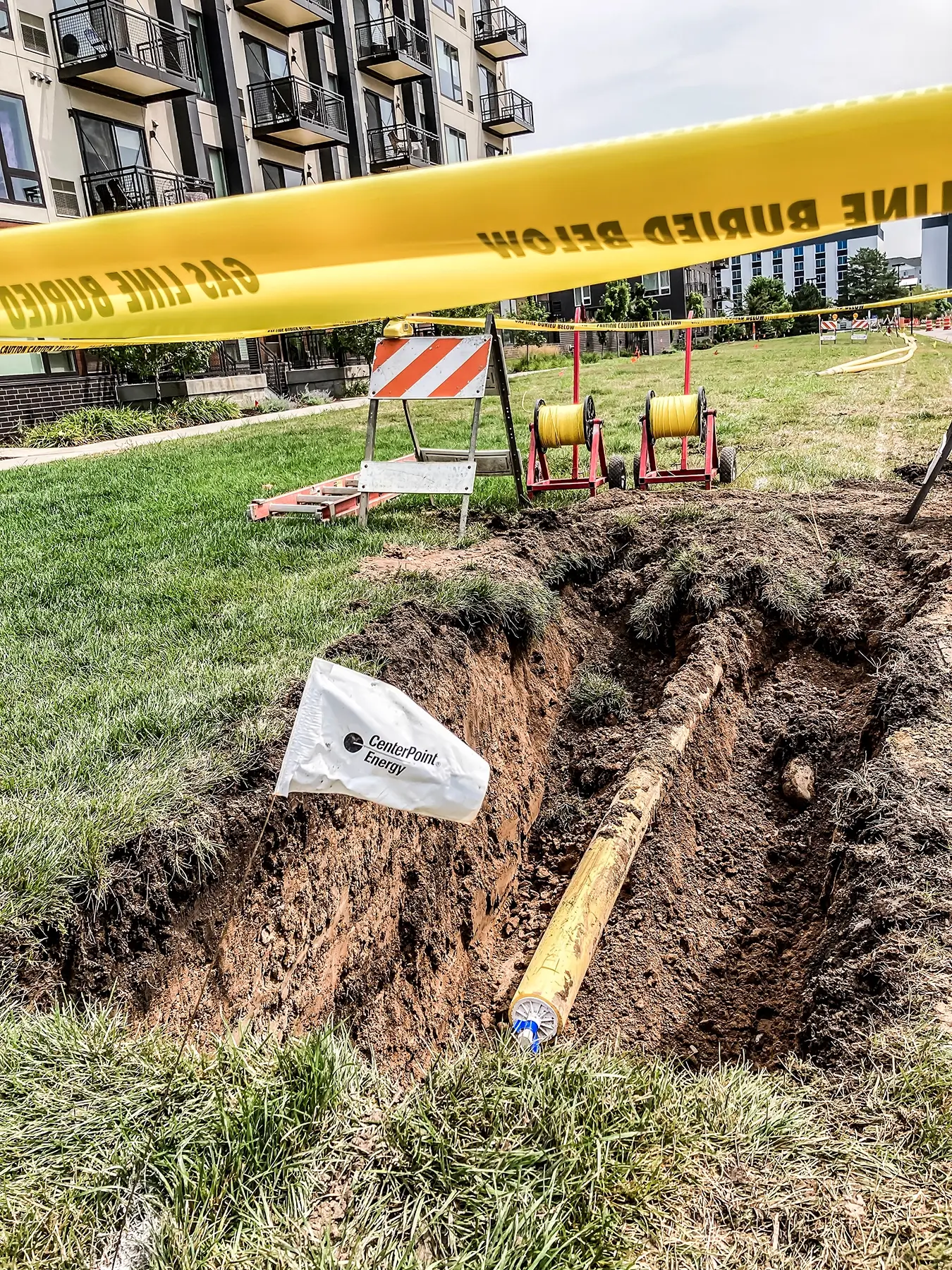 A small diameter pipeline exposed in a small trench behind caution tape.