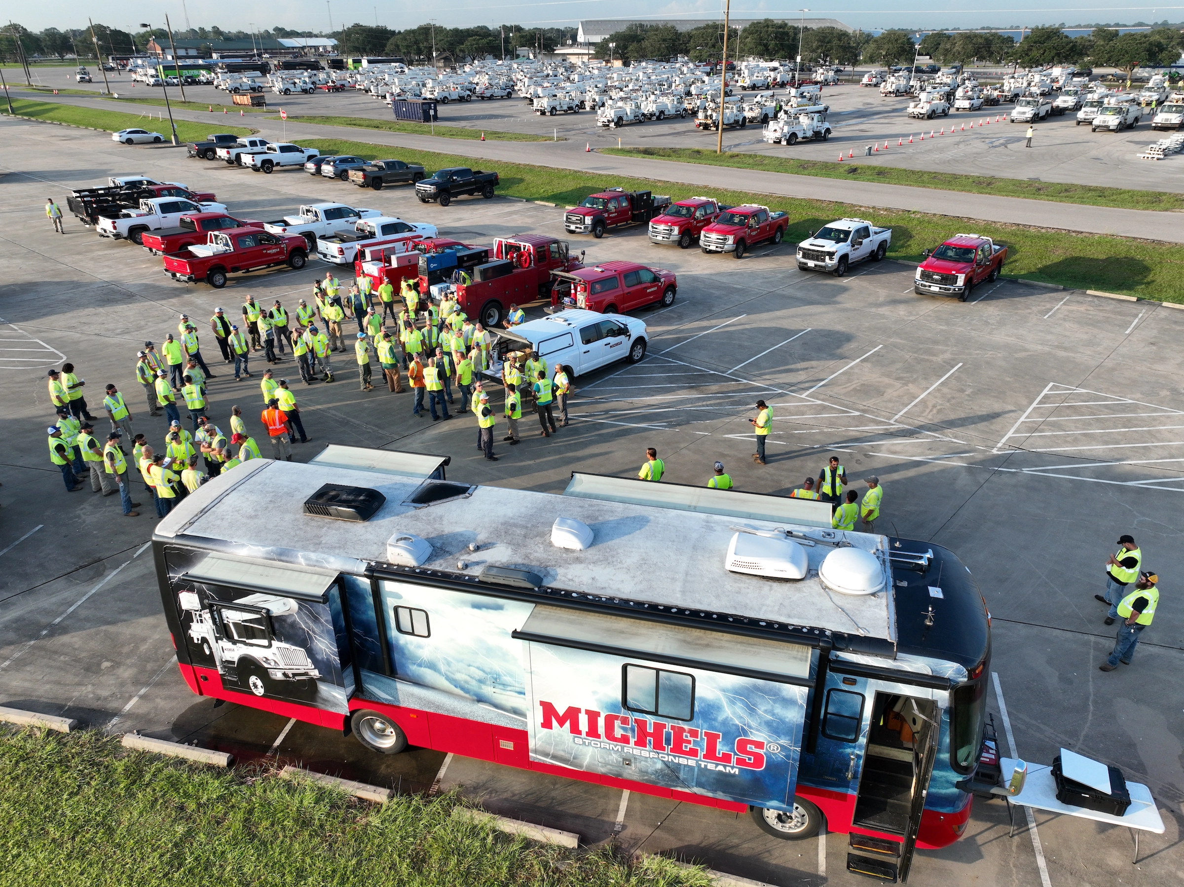 A large group of crew members stand outside the Michels storm response RV.