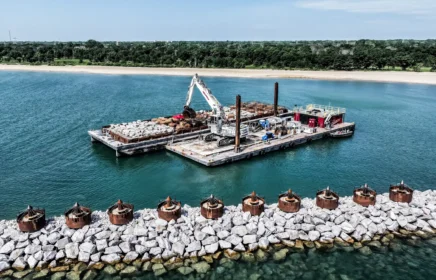 A platform barge carries an excavator off the coast of Lake Michigan