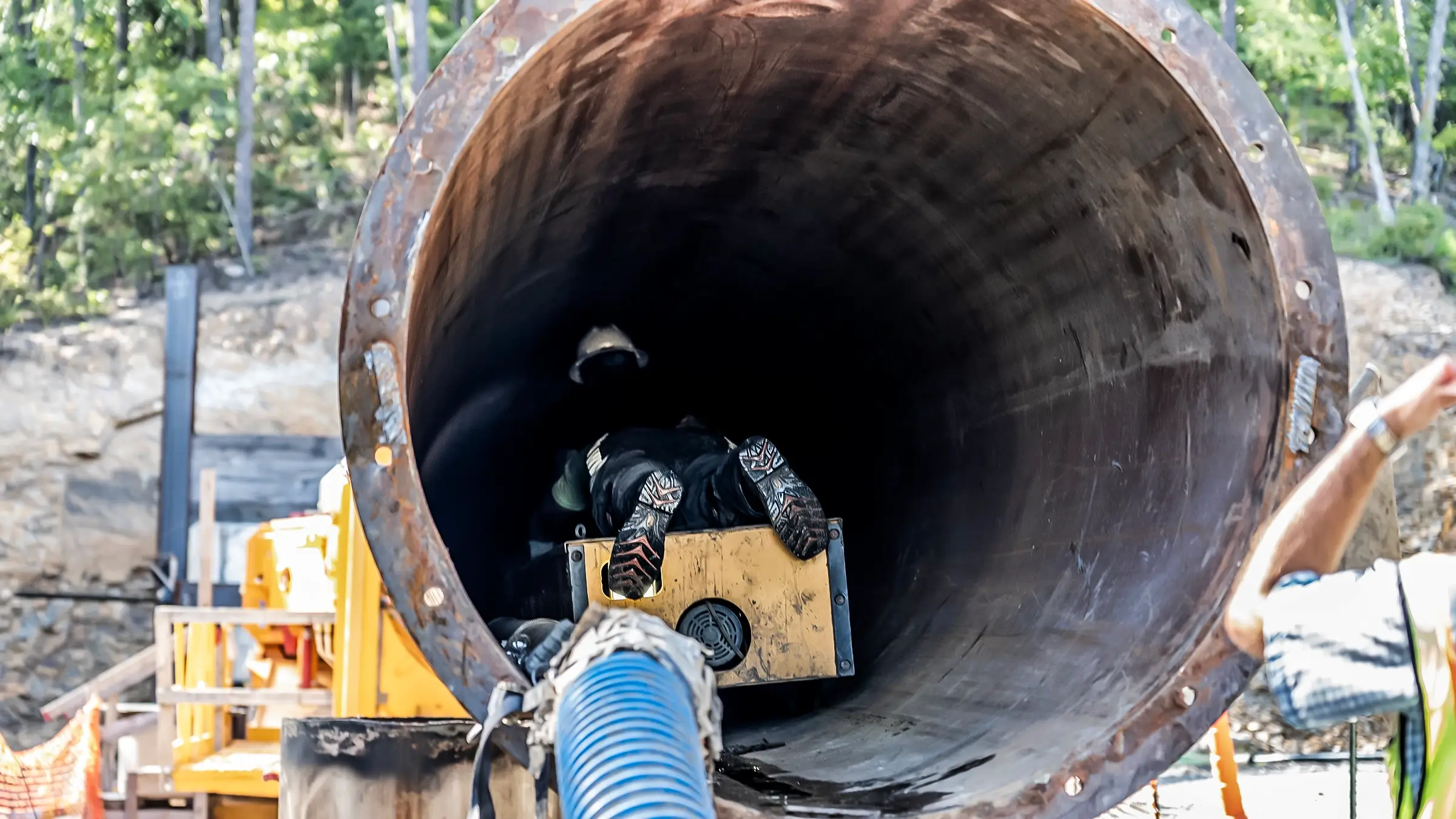 A crew worker inspects the inside diameter of a large portion of pipe.