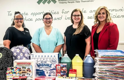 Four women standing around donated school supplies.