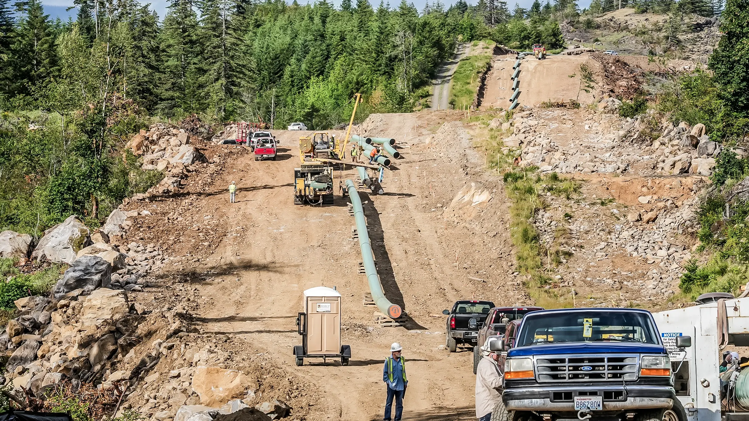 Pipeline being strung together with crew members nearby.