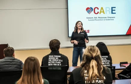 A woman stands speaking to a small crowd at CARE training.