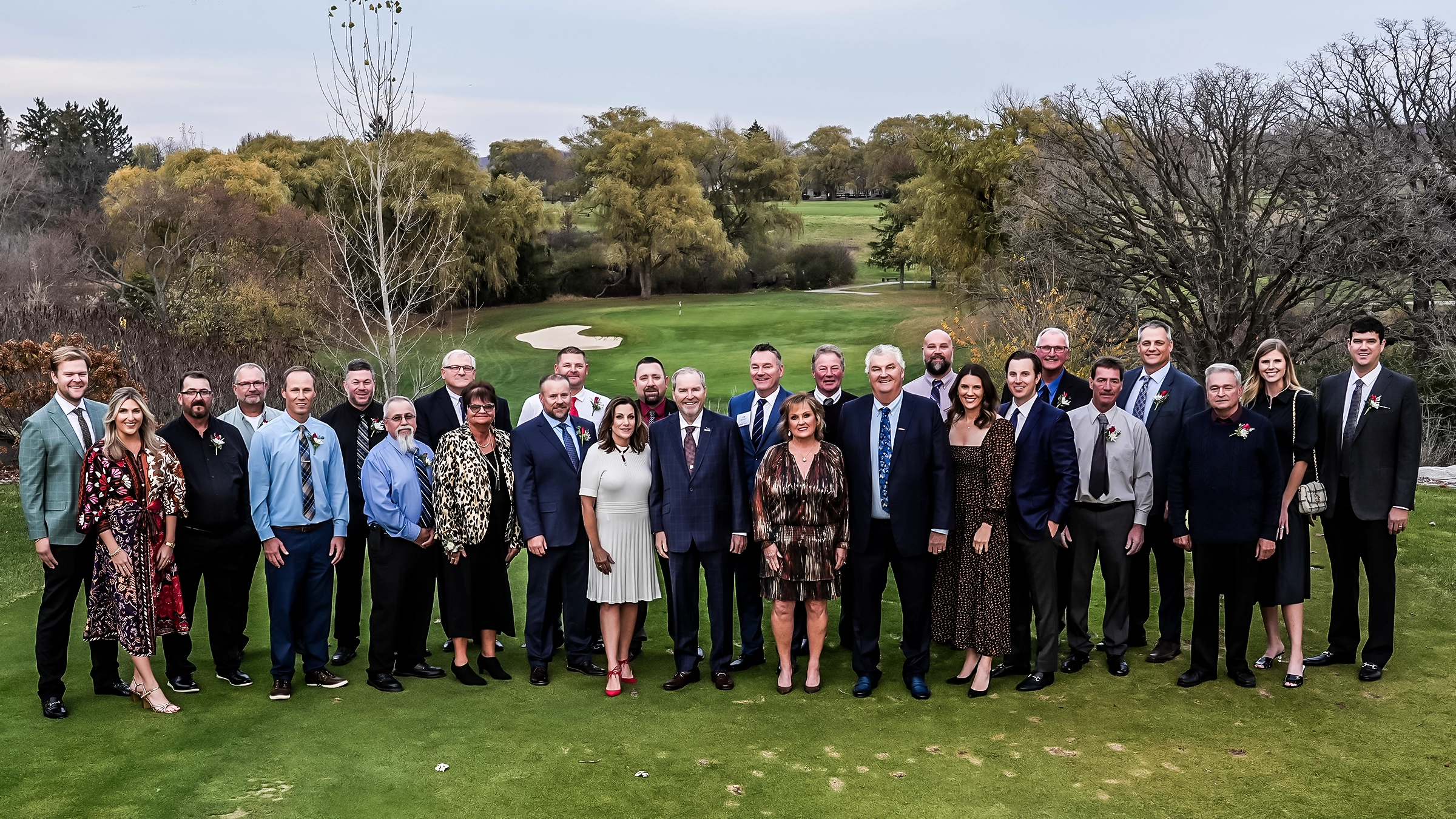 Large group of people standing on a golf tee box.