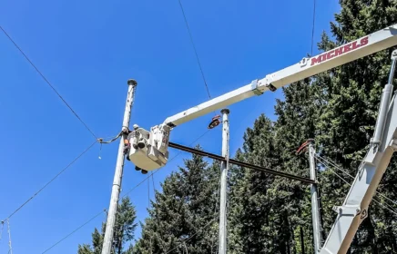 Crew members in a bucket truck work on a transmission pole line.