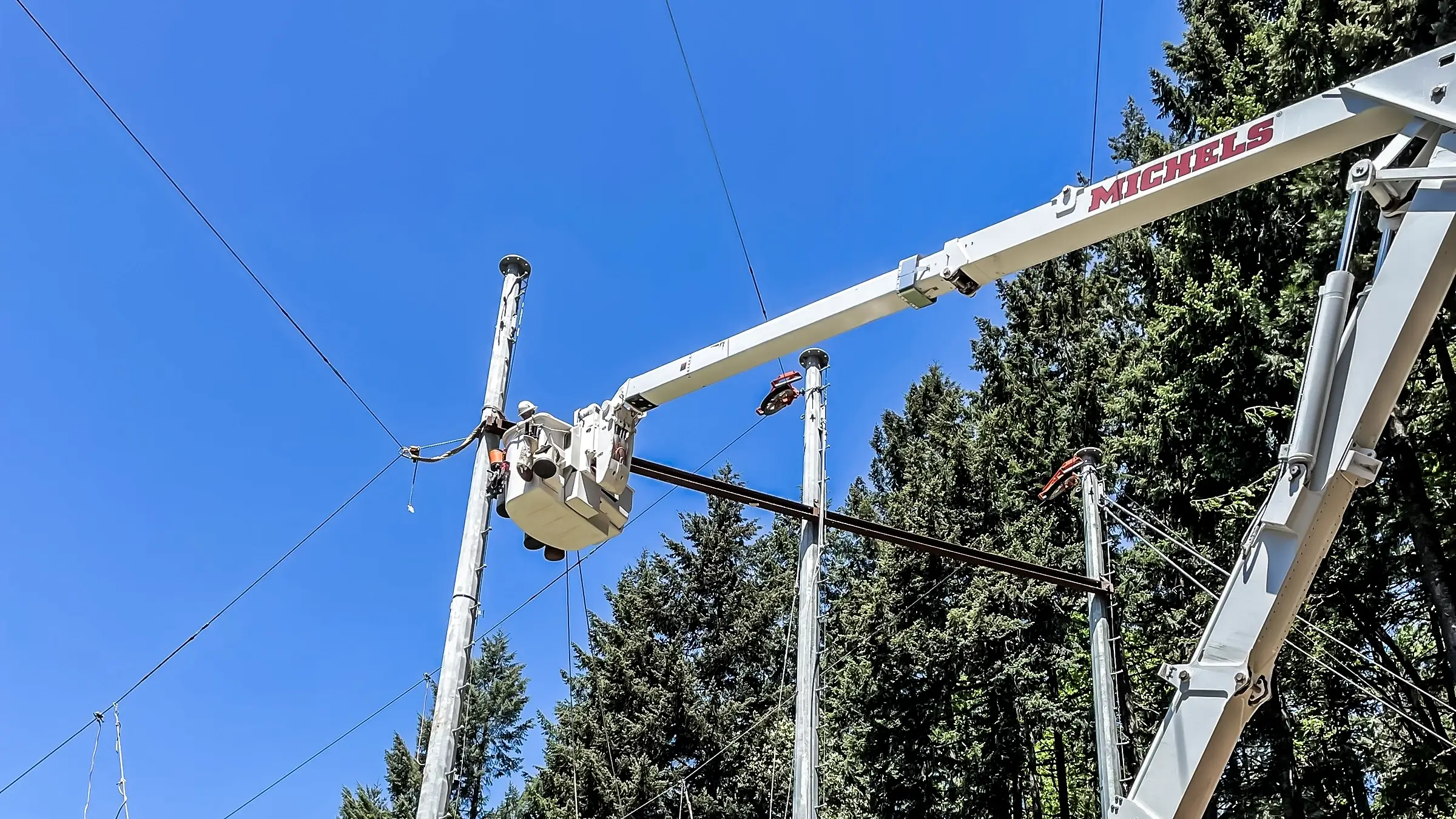 Crew members in a bucket truck work on a transmission pole line.