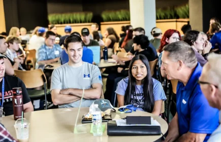 Several students sit around a table smiling.