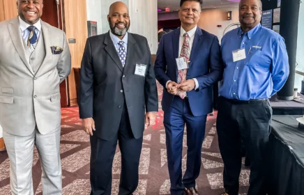 Four men in suits stand in a group at a Supplier Diversty event.