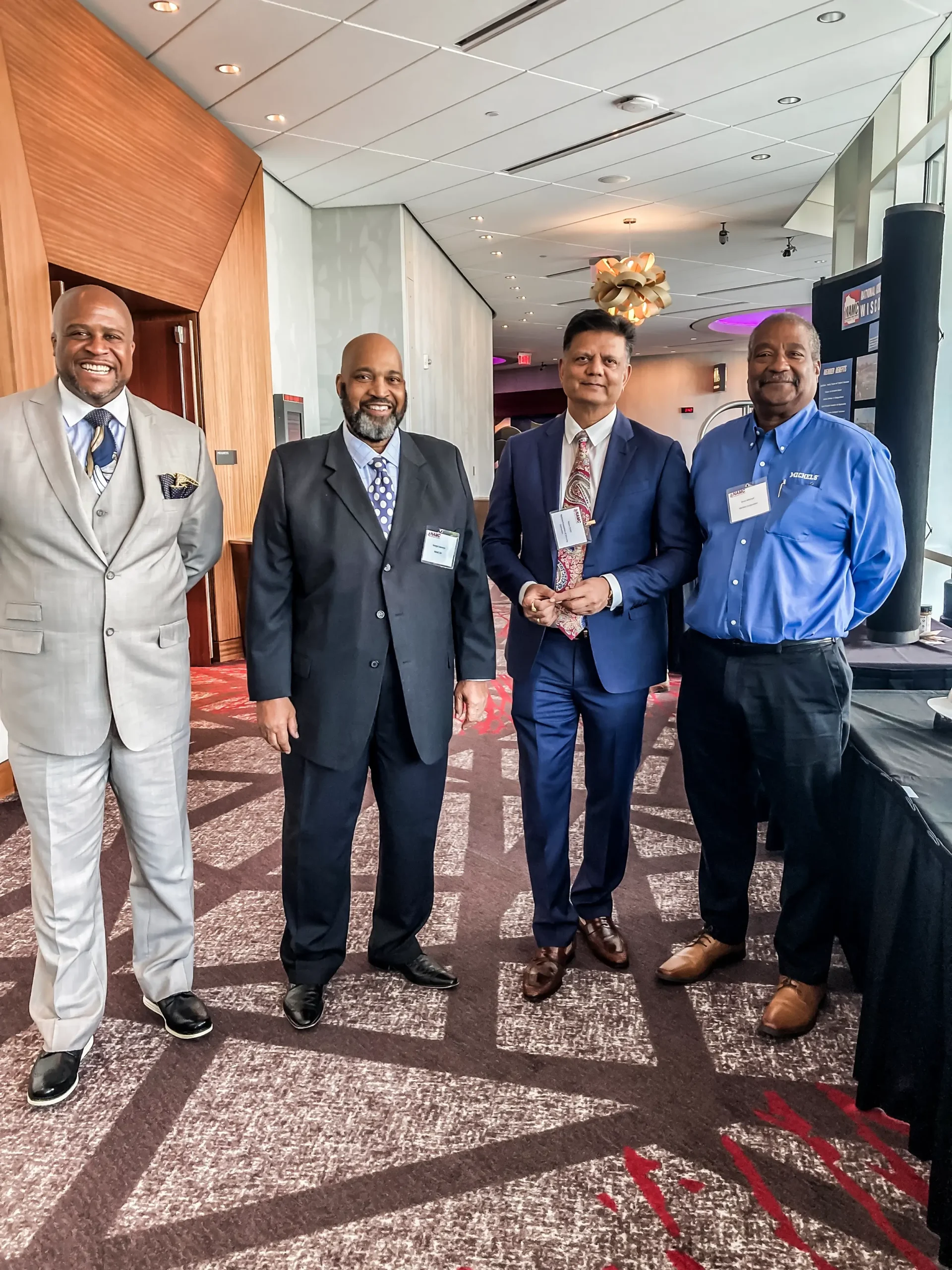 Four men in suits stand in a group at a Supplier Diversty event.