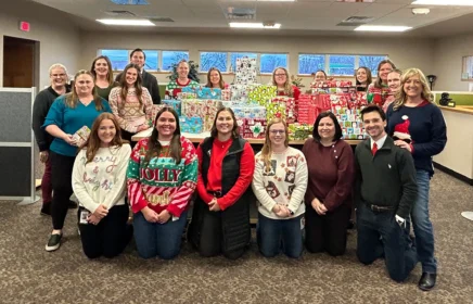 Michels marketing team stands around a pile of wrapped gifts.