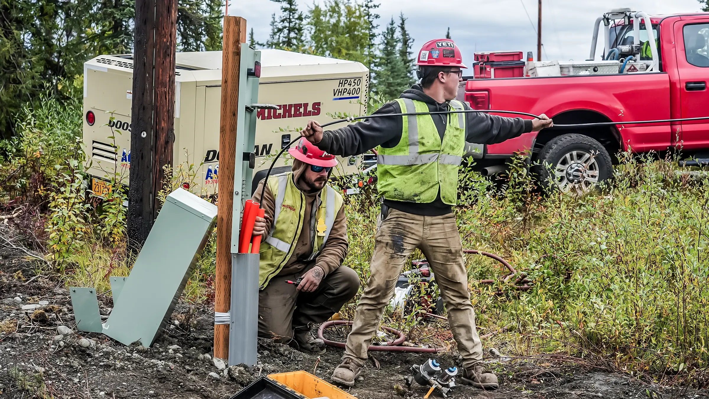 Two crew members assist in laying out small cable.