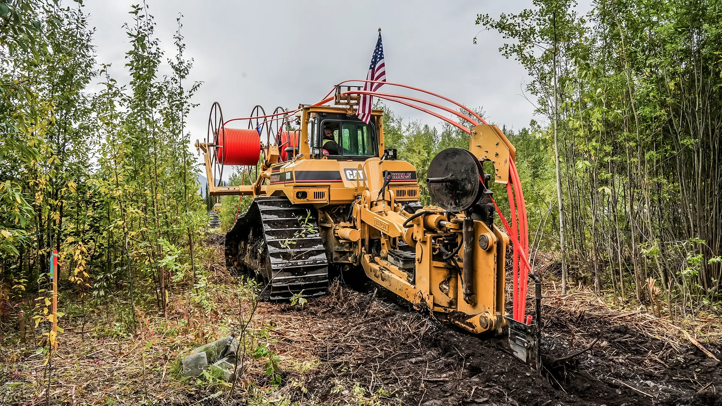 A cable plowing rig with an American flag on top of it.