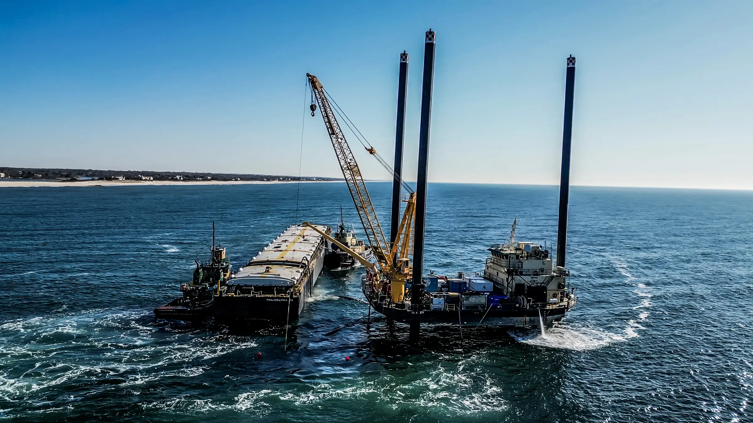 A large crane works off a barge onto a ship.