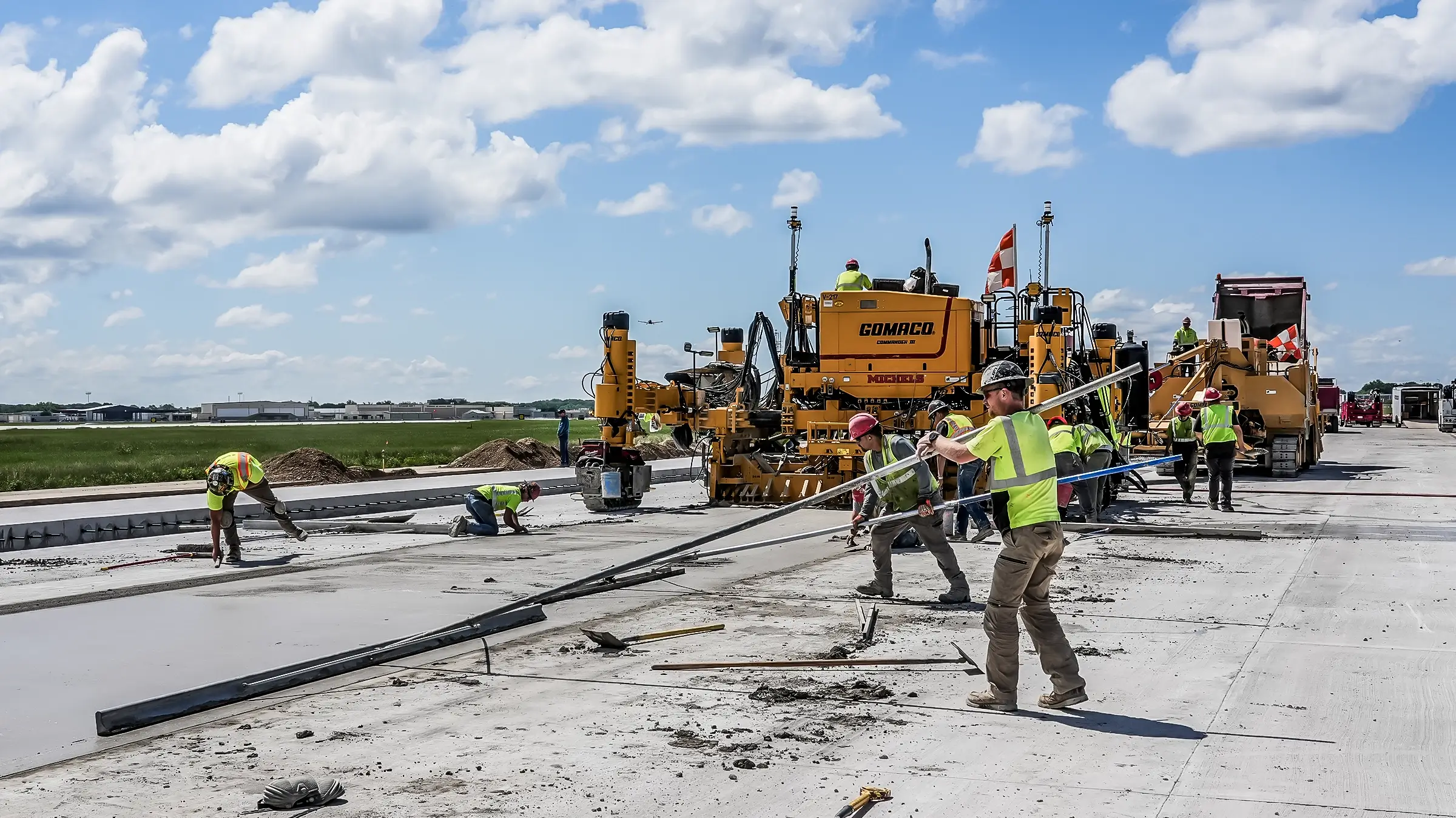 Airport paving crew lays out concrete on runway.