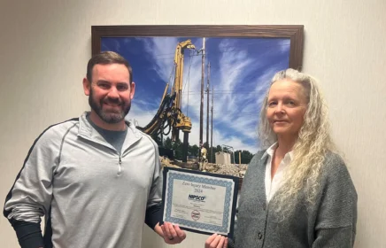 Man and woman hold up award frame.